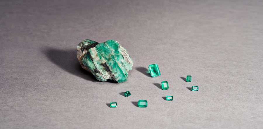 Emerald rough and faceted emeralds on a neutral surface