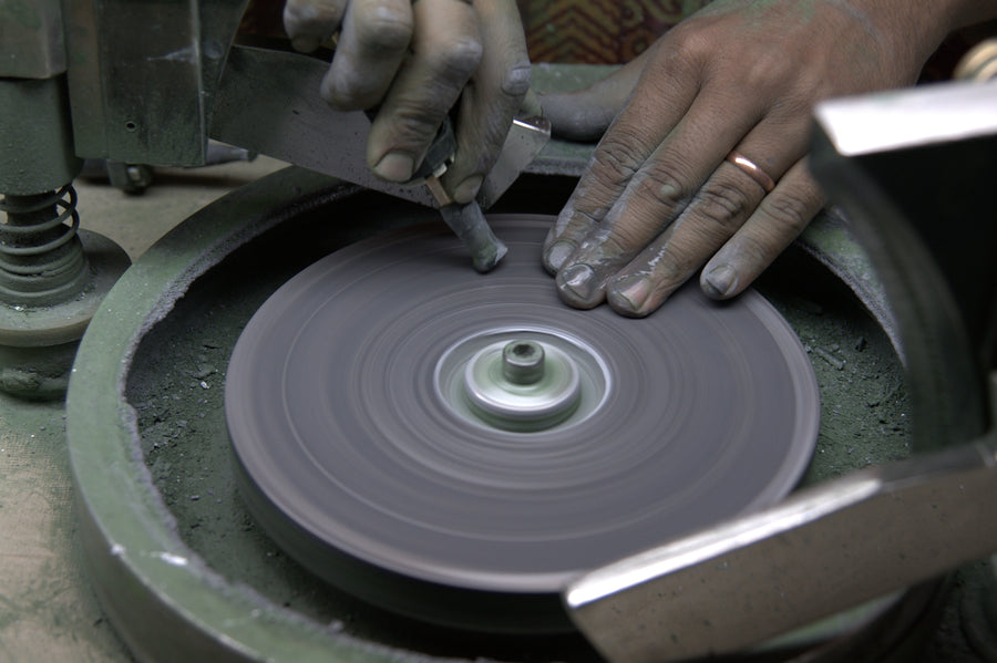 A cutter guiding an emerald against a flat polishing lap